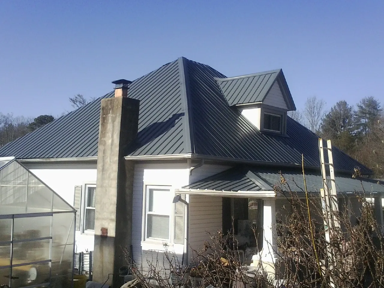 Dark blue standing seam metal roof on a white farmhouse with dormer — Slate & Tile Roof Repair by Roofing Brothers in Casa Grande