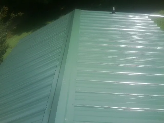 New green metal panels meeting at the ridge of a roof — Flat Roof Repair work by our crew in Casa Grande