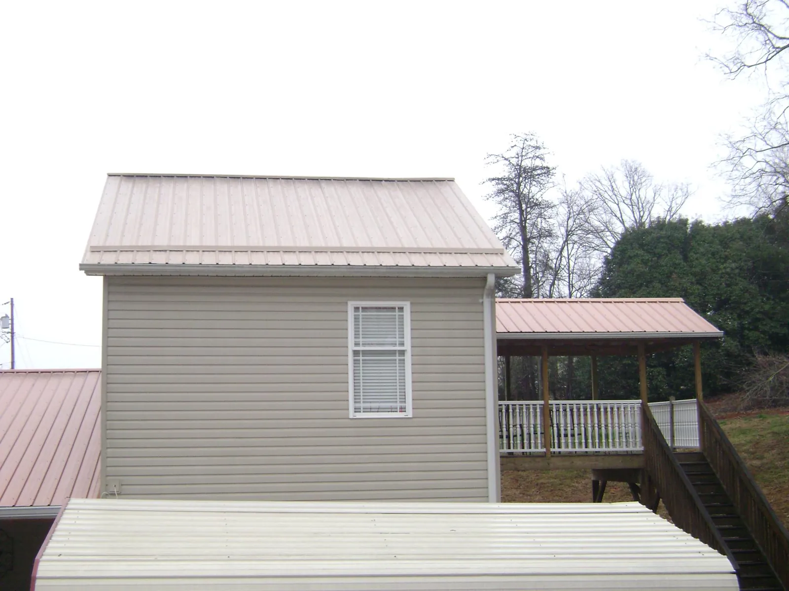Tan metal roofs on a two story addition and attached porch, from a Roof Replacement job in Casa Grande