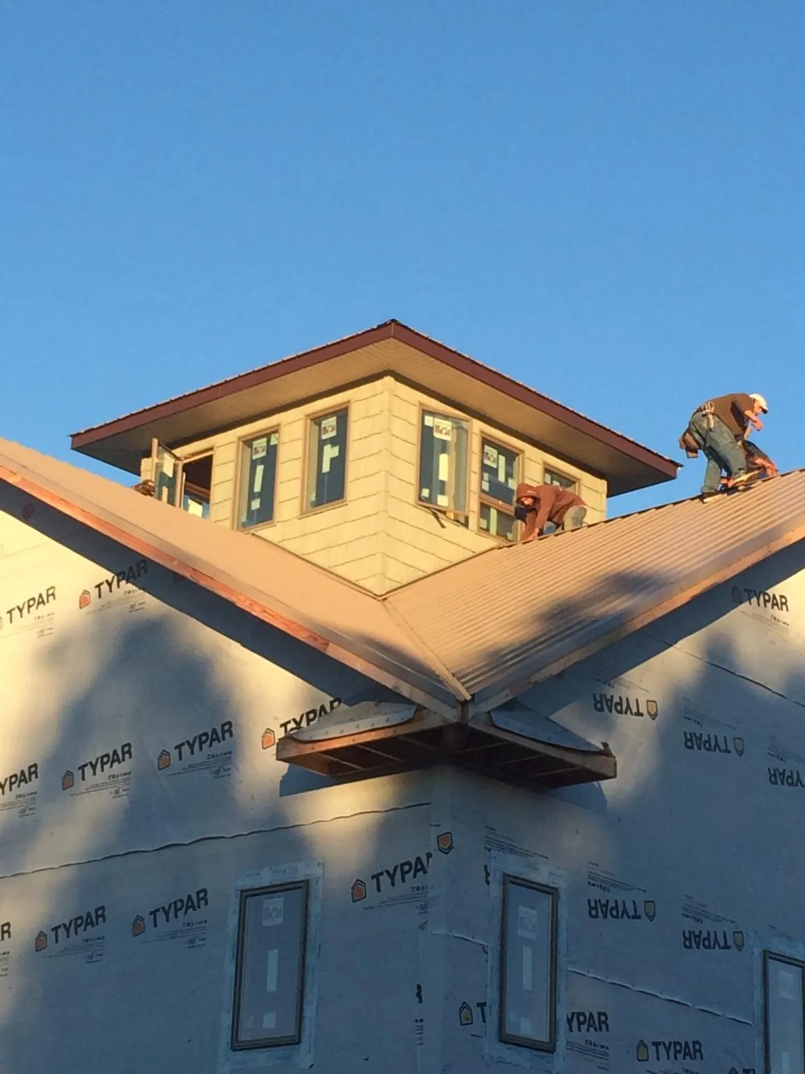 Roofers working around a rooftop cupola on a new metal roof at sunset — Roof Waterproofing in Casa Grande by Roofing Brothers
